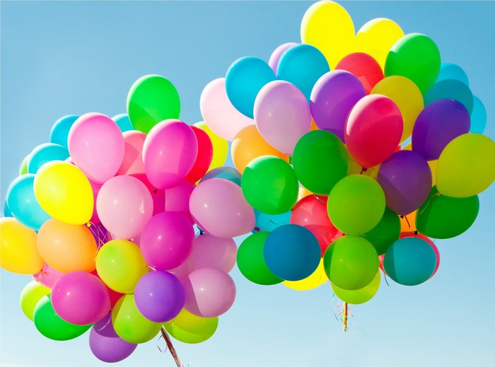 A large group of colorful balloons against a blue sky