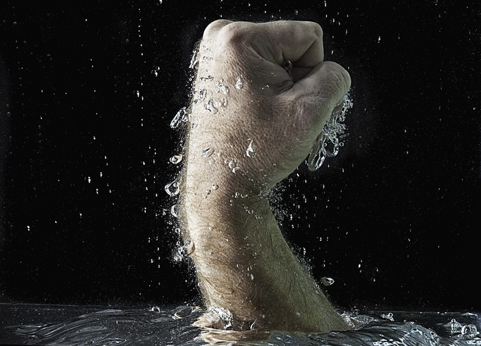 Fist emerging from water with splashes