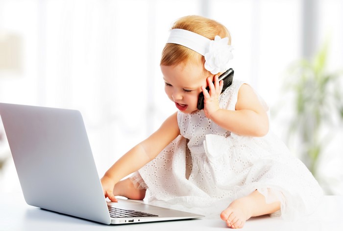 Baby girl on phone with laptop