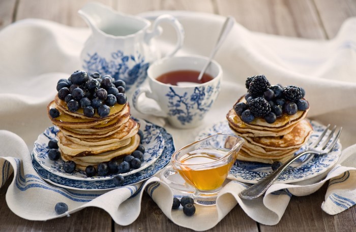 Pancakes with blueberries and blackberries, tea, and honey
