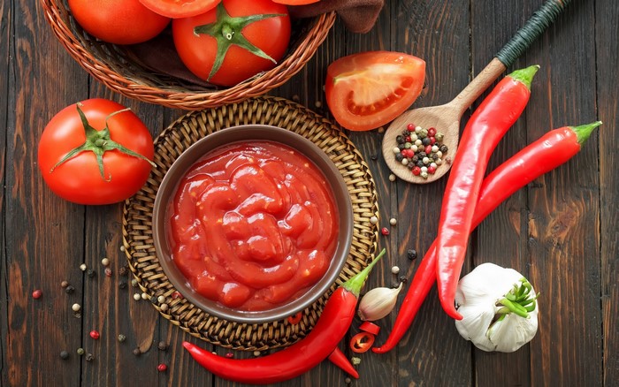 Tomatoes, chili peppers, garlic, and peppercorns on a wooden table
