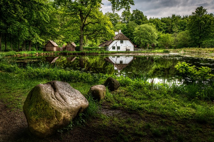 White house and wooden huts by a pond in Germany