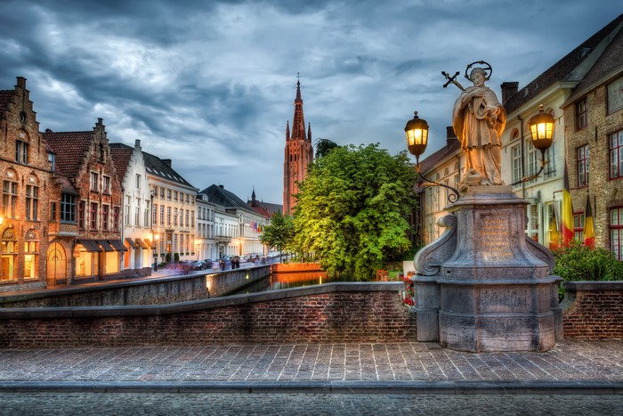 Bruges, Belgium canal with statue and church tower