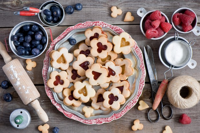 Flower-shaped cookies with jam and berries on a wooden table