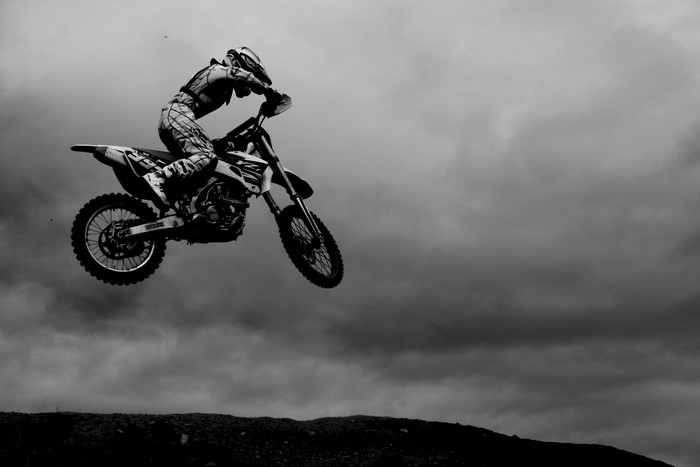 Motorcyclist performing a jump against a cloudy sky