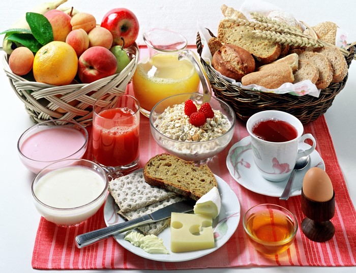 Breakfast still life with fruits, bread, cheese, and drinks