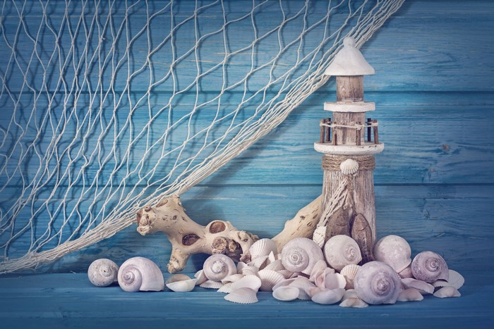 Seashells and lighthouse decoration on blue wooden background