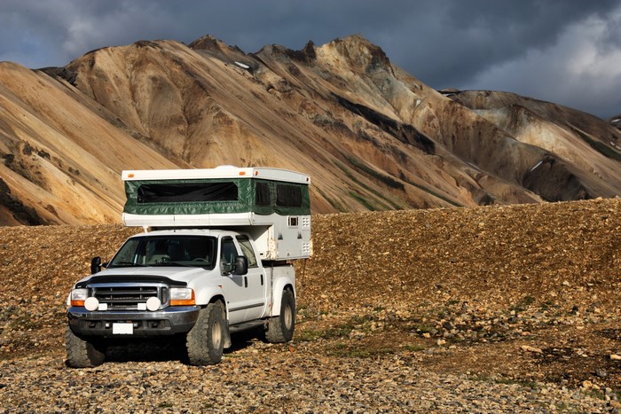 White pickup truck with camper in mountains