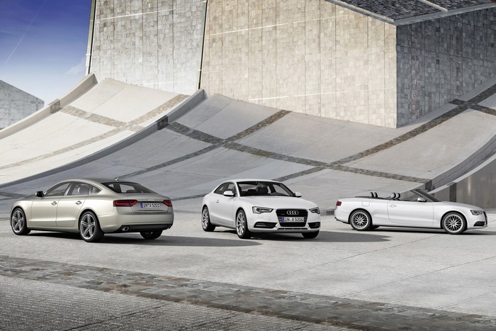 Three Audi A5 models in front of a modern building