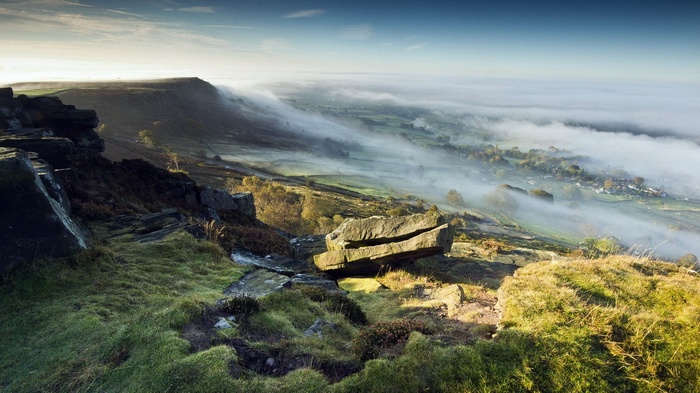 Misty valley with rocky foreground and distant village
