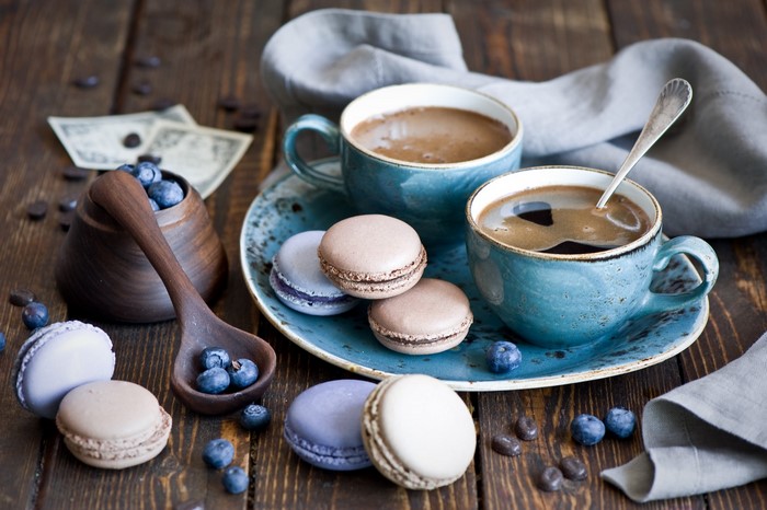 Two cups of coffee with macarons and blueberries