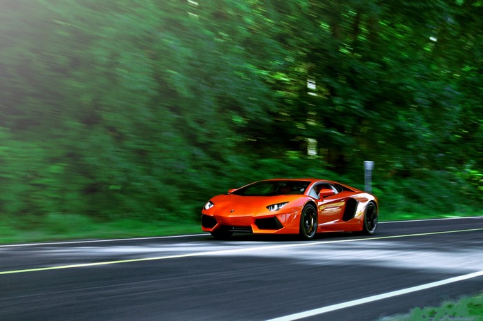 Orange Lamborghini Aventador LP700-4 driving on a road