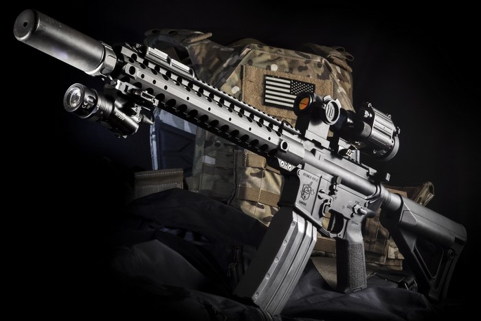 AR-15 rifle with suppressor, tactical vest, and optics