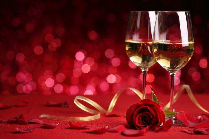 Two glasses of white wine with a rose and petals