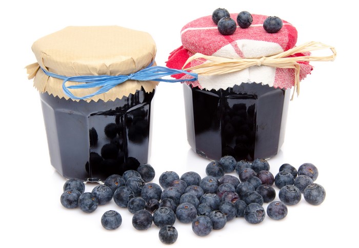 Two jars of blueberry jam with fresh blueberries