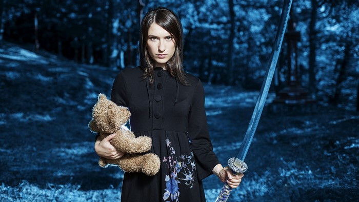 Woman holding a teddy bear and a sword