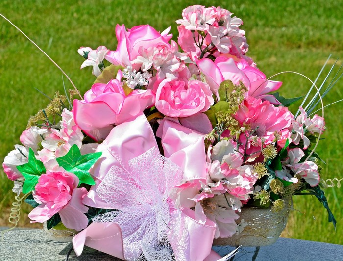 Pink floral arrangement with bow on a grave