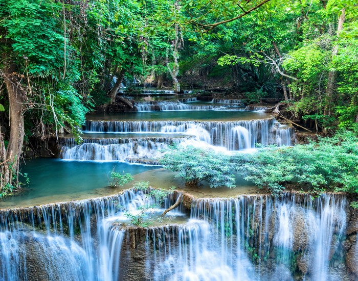 Tiered waterfalls cascading through a lush green forest