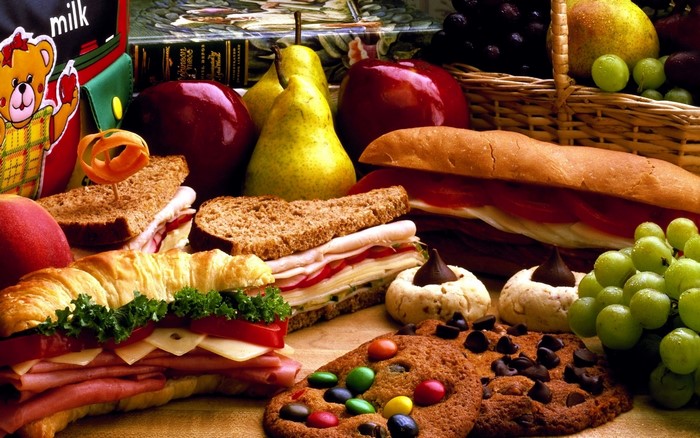 Picnic basket with sandwiches, fruits, and cookies