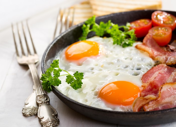 Fried eggs with bacon and tomatoes in a pan
