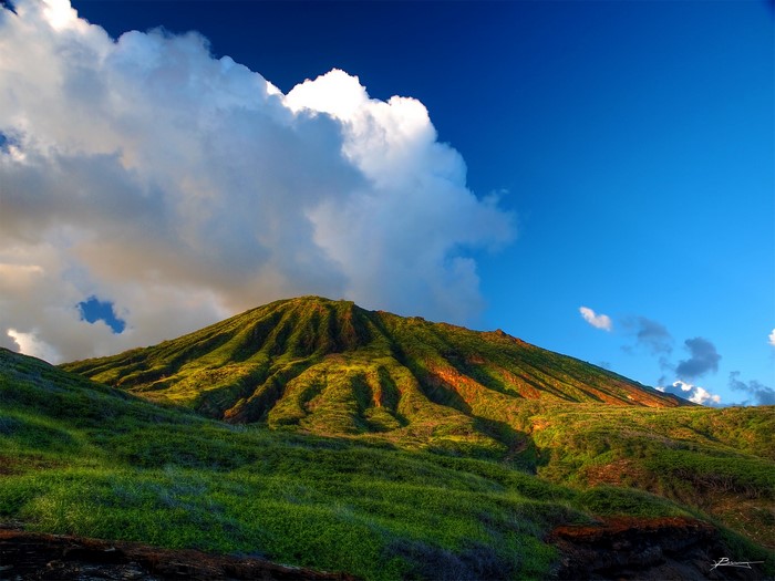 Green mountain slopes under a blue sky with clouds in Hawaii