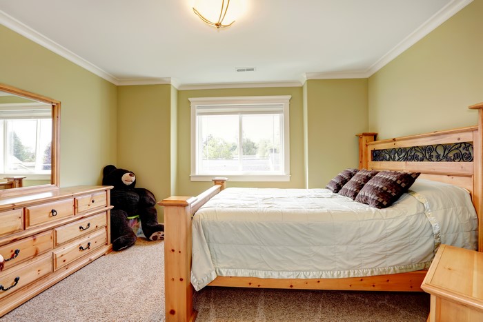 Bedroom with wooden furniture and a large teddy bear