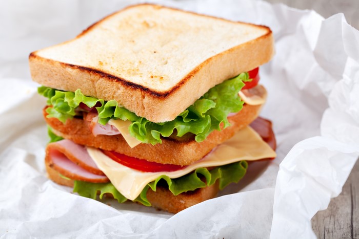 Triple-decker sandwich with ham, cheese, lettuce, and tomato