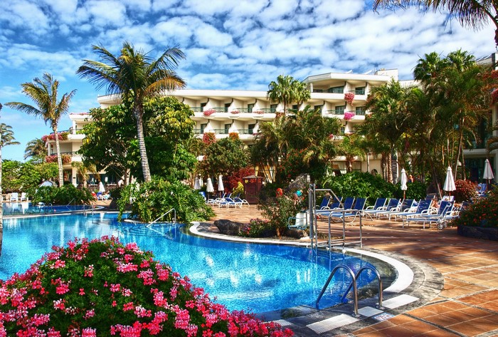 Hotel with swimming pool and palm trees in Playa Blanca, Spain
