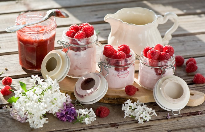Raspberry jam and yogurt in jars with lilac and a jug