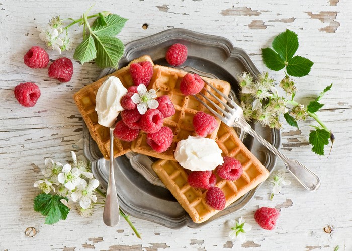 Still-life of waffles with raspberries and cream
