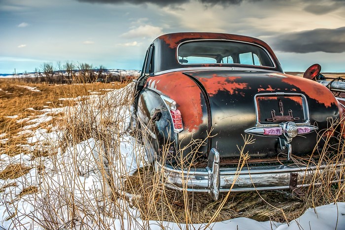 Abandoned vintage car in a snowy field