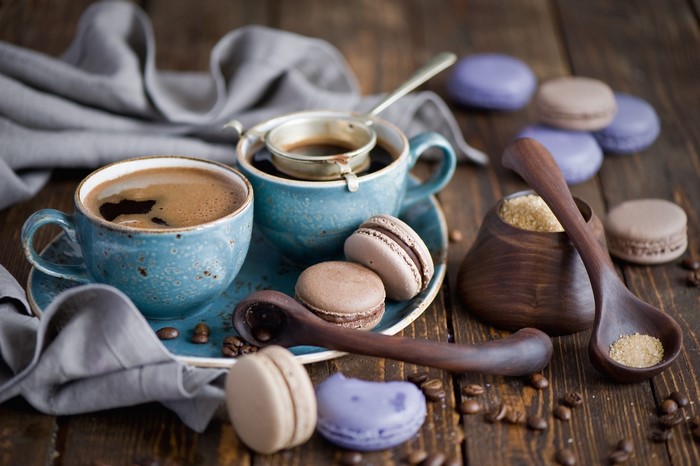 Two cups of coffee with macarons and sugar