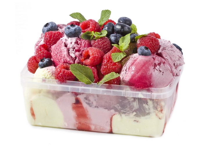 Container of mixed berry ice cream with fresh berries and mint