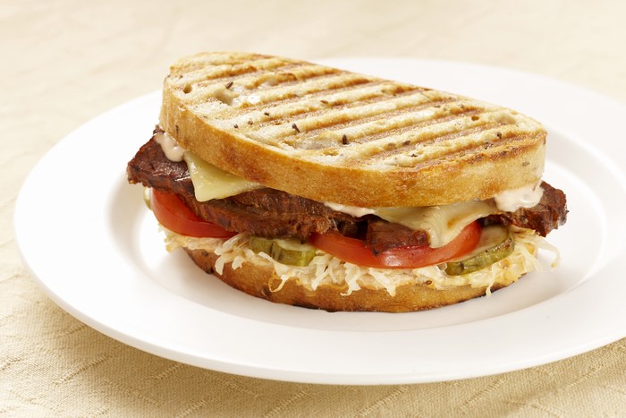 Grilled sandwich with meat, cheese, and vegetables