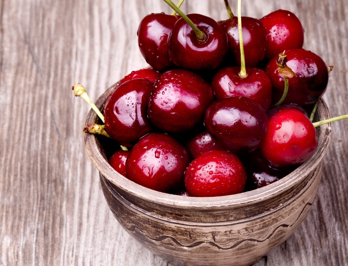 Bowl of fresh cherries on a wooden table