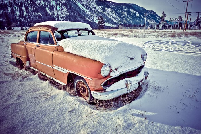 Abandoned vintage car covered in snow