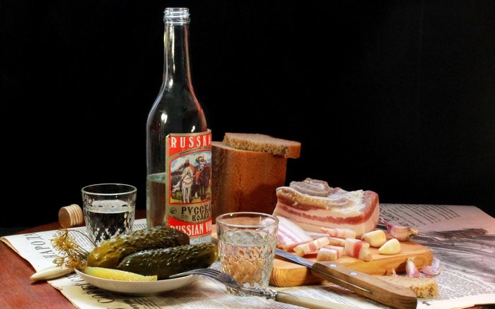 Still life with vodka, pickles, bread, and bacon