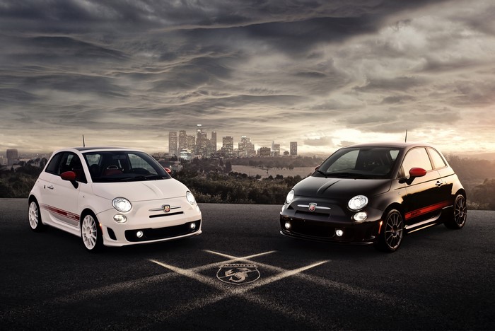 Two Fiat 500 Abarth cars, black and white, with Los Angeles skyline