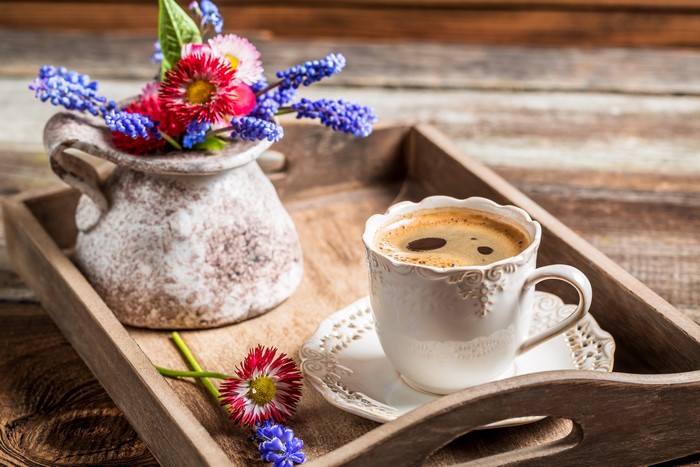 Coffee cup and flowers on a wooden tray