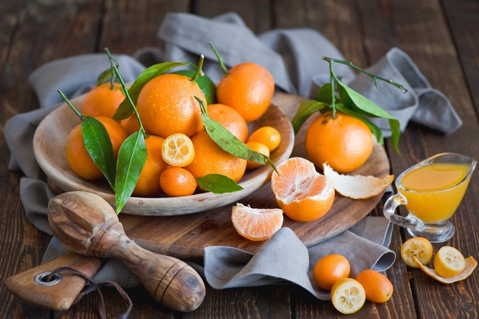 Tangerines and kumquats with juice and juicer