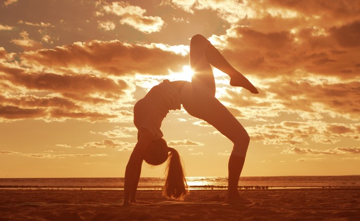 Girl doing yoga on the beach at sunset