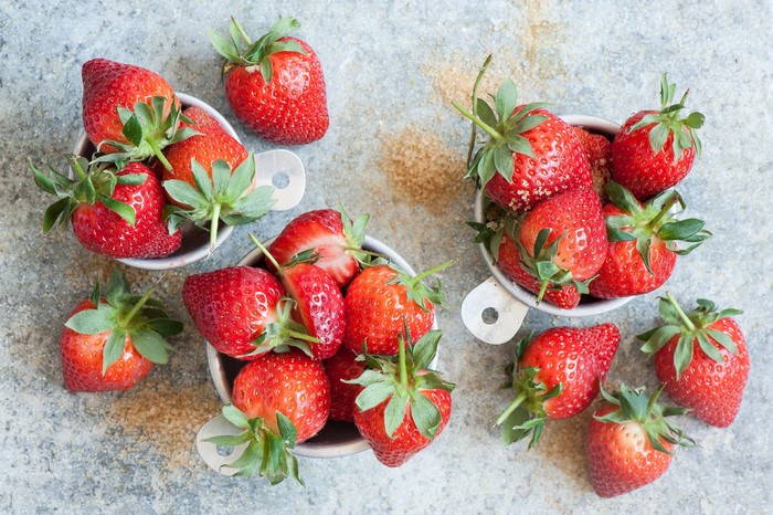 Strawberries in measuring cups with sugar