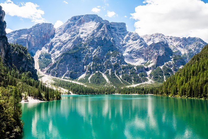Turquoise lake in front of majestic mountains and green forest