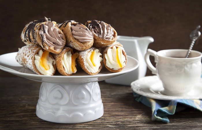 Cannoli pastries on a cake stand with coffee
