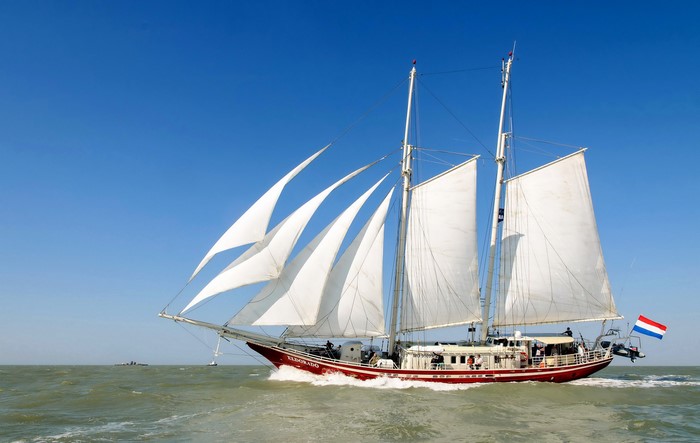 Red El Dorado sailboat with white sails on the sea