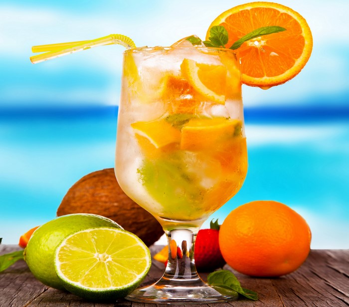 Refreshing Orange and Lime Drink with Fruits on a Beach Background