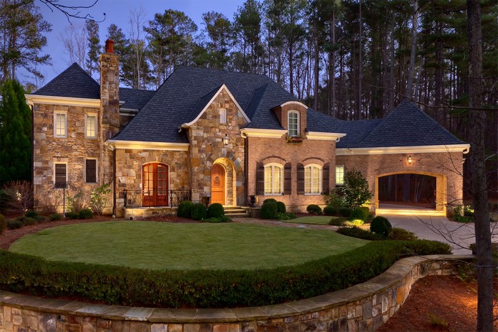 Luxury stone and brick house at night with manicured lawn