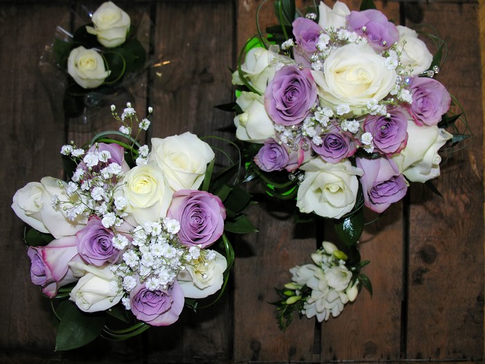 Two bouquets of white and purple roses with a boutonniere