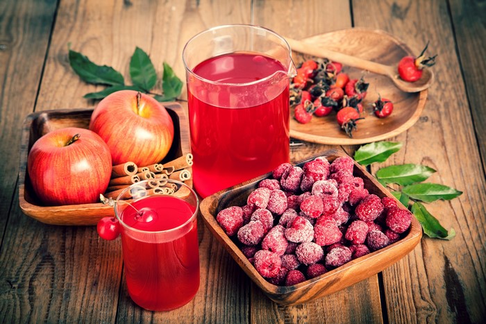Still-life of juice, apples, raspberries, and rose hips