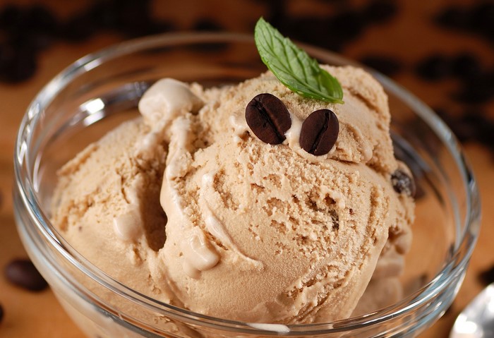 Coffee ice cream in a glass bowl with coffee beans and mint
